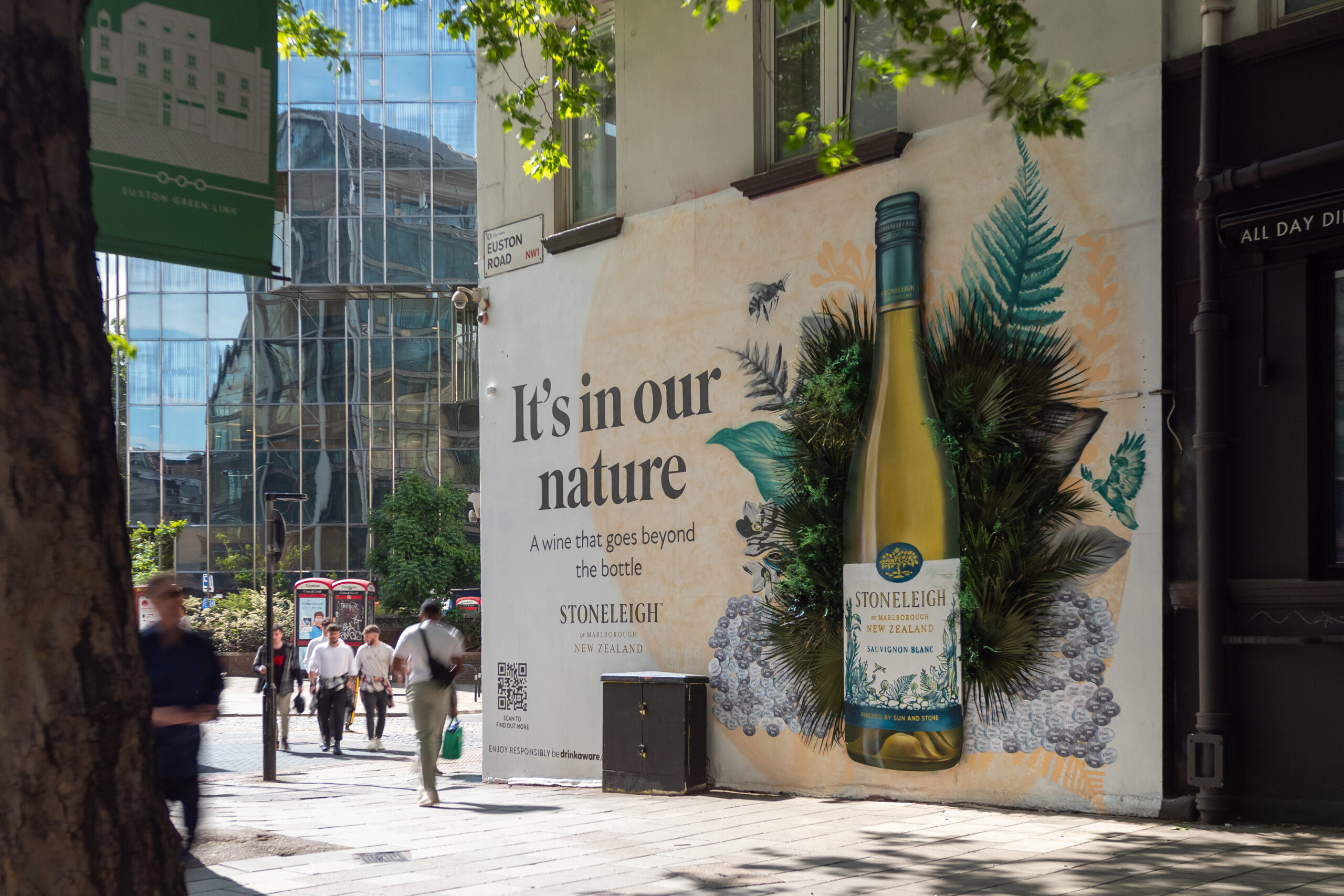 A large billboard with wine advert and preserved foliage