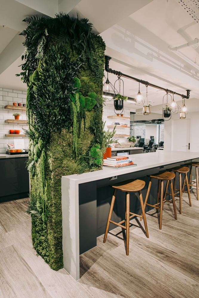 An organic moss column with a worktop and kitchen in the background