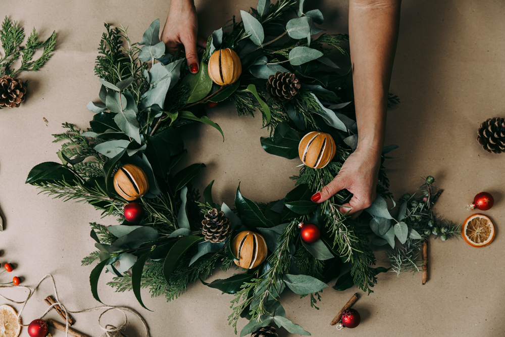 Hands making a festive Christmas wreath